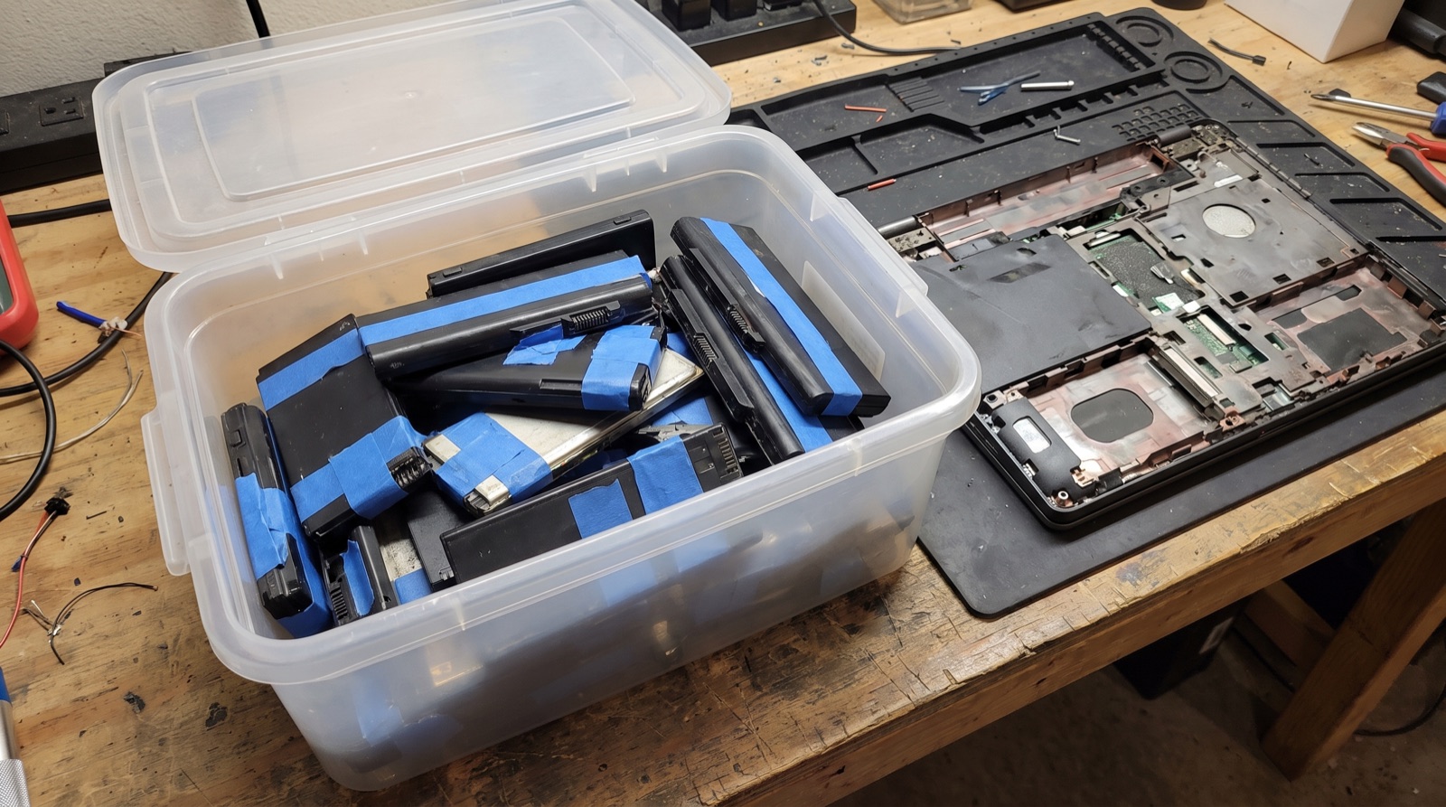 Entnommene Notebook- und Handyakkus liegen mit abgeklebten Polen in einer verschlossenen Sammelbox.
